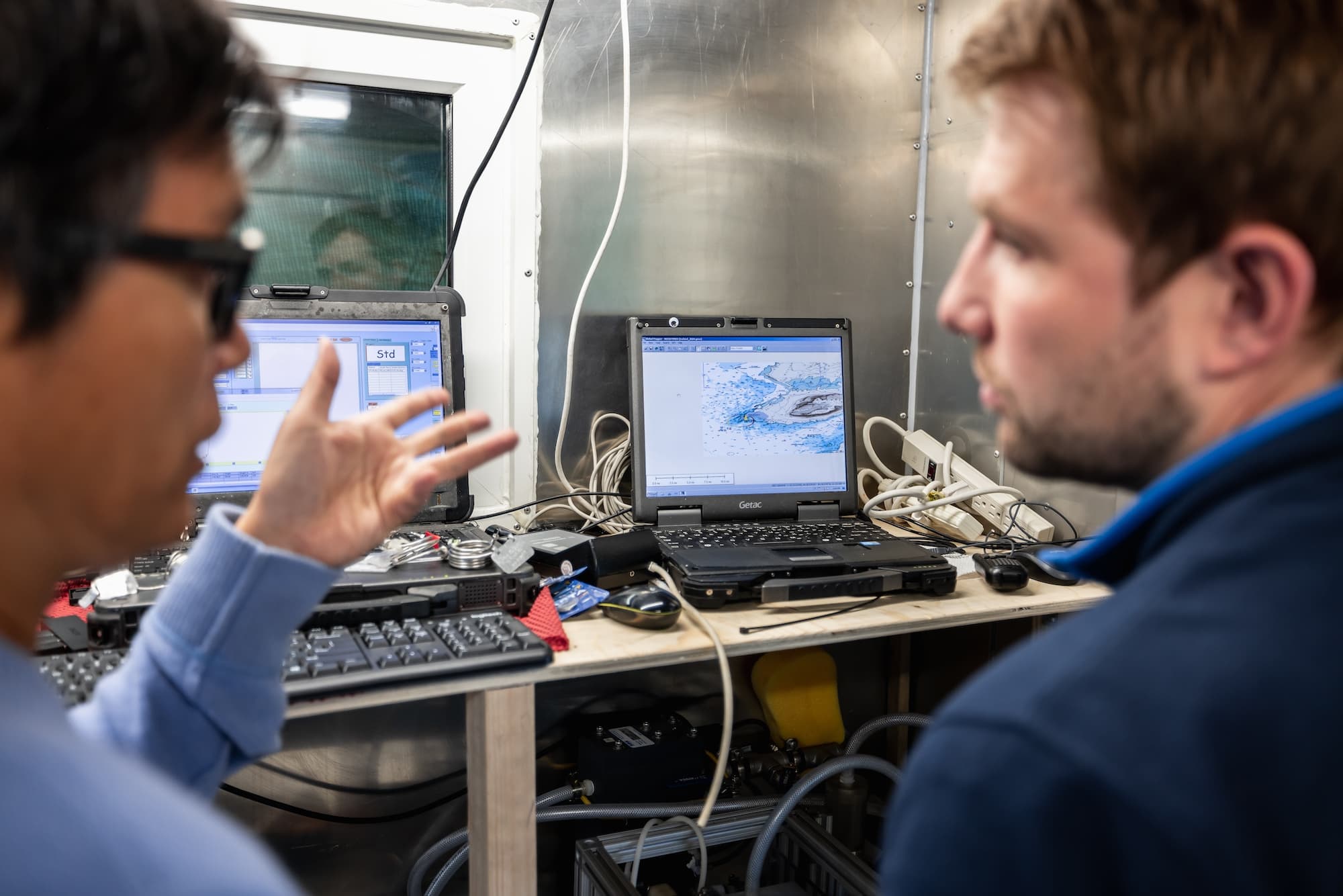 David Ho og Lennart Bach ræða um vísindin innan um borð í sérsmíðaðri rannsóknastofu Rastar.